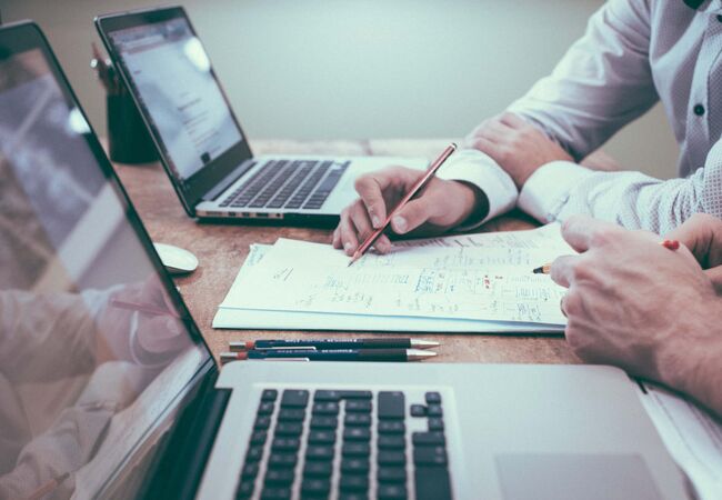 Seitenansicht eines Schreibtisches mit zwei arbeitenden Personen